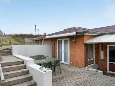 a house with a patio with a table and chairs at Holiday Home Fris - 100m from the sea by Interhome in Torsted