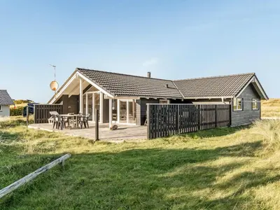 a wooden house with a deck and a table at Holiday Home Horsten - 350m from the sea by Interhome in Torsted