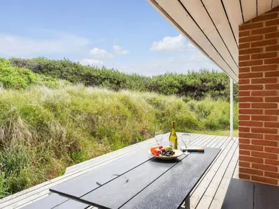 a table with a bowl of fruit and a bottle of wine at Holiday Home Annemia - 200m from the sea by Interhome in Torsted