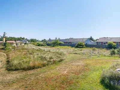 a field of grass with houses in the background at Holiday Home Tameran - 700m from the sea by Interhome in Torsted