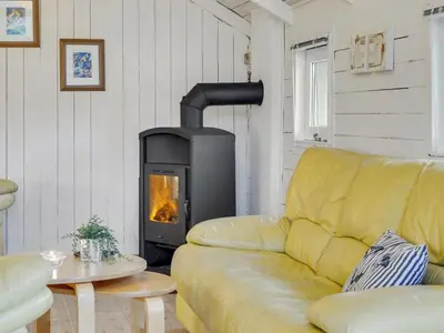a yellow couch in a living room with a fireplace at Holiday Home Tameran - 700m from the sea by Interhome in Torsted
