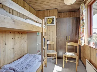 a bedroom with a bunk bed and a chair at Holiday Home Chumani - 900m from the sea by Interhome in Torsted