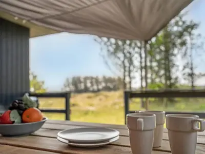a table with plates and cups and a bowl of fruit at Holiday Home Chumani - 900m from the sea by Interhome in Torsted