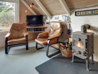 a living room with two chairs and a stove at Holiday Home Algonda - 500m from the sea by Interhome in Torsted