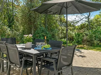 a black table with chairs and an umbrella at Holiday Home Aslak - 350m from the sea by Interhome in Torsted