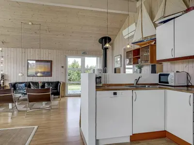 a kitchen with white cabinets and a living room at Holiday Home Emppu - 400m from the sea by Interhome in Torsted