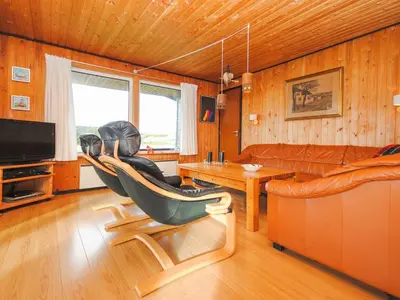 a person sitting in a chair in a living room at Holiday Home Gisela - 250m from the sea by Interhome in Torsted