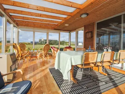 a dining room with a table and chairs and windows at Holiday Home Gisela - 250m from the sea by Interhome in Torsted