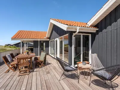 a wooden deck with chairs and a table at Holiday Home Milena - 600m from the sea by Interhome in Torsted