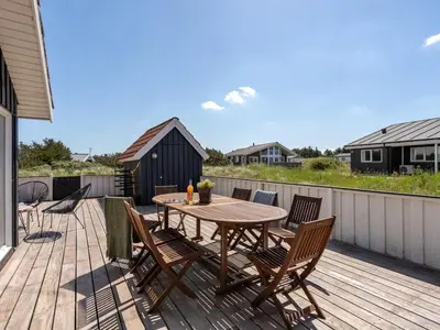 a wooden deck with a wooden table and chairs at Holiday Home Milena - 600m from the sea by Interhome in Torsted