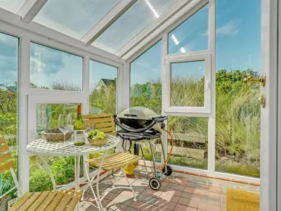 a screened in porch with a grill and a table and chairs at Holiday Home Quirina - 75m from the sea by Interhome in Torsted