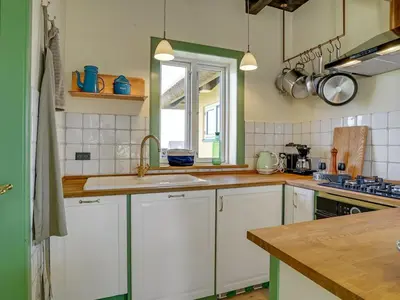 a kitchen with white cabinets and a sink and a window at Holiday Home Quirina - 75m from the sea by Interhome in Torsted
