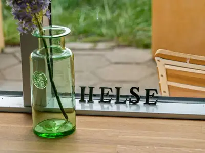 a green vase with flowers in it sitting on a table at Holiday Home Quirina - 75m from the sea by Interhome in Torsted