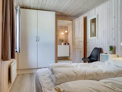 a bedroom with two beds and a black chair at Holiday Home Afke - 900m from the sea by Interhome in Torsted