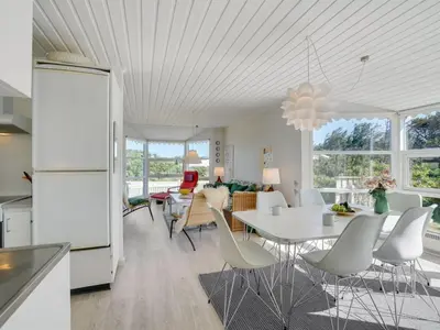 a kitchen and living room with a white table and chairs at Holiday Home Majgull - 150m from the sea by Interhome in Torsted