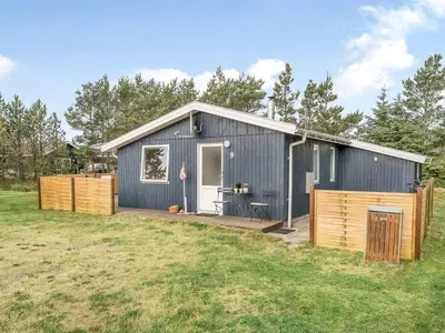 a gray house with a wooden deck in a field at Holiday Home Hughlek - 900m from the sea by Interhome in Torsted