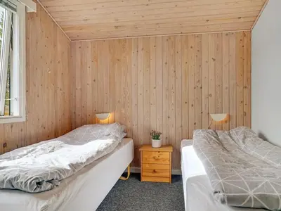 two beds in a room with wooden walls at Holiday Home Hughlek - 900m from the sea by Interhome in Torsted