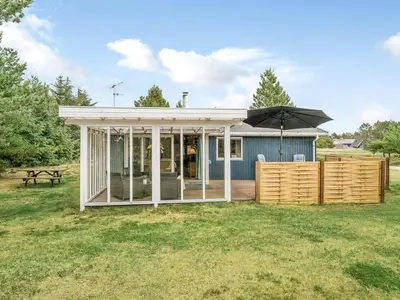 a small house with an umbrella in the yard at Holiday Home Hughlek - 900m from the sea by Interhome in Torsted