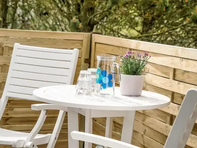 a white table and chairs on a patio with flowers at Holiday Home Hughlek - 900m from the sea by Interhome in Torsted