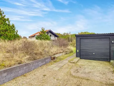 a garage with a black door on the side of a house at Holiday Home Viktorija - 800m from the sea by Interhome in Torsted