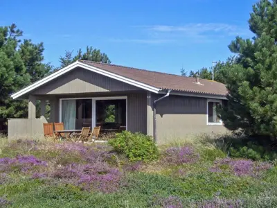 a small house with chairs in a field of flowers at Holiday Home Tuovi - 800m from the sea by Interhome in Torsted