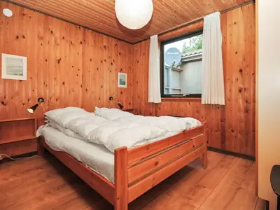 a bed in a room with wooden walls and a window at Holiday Home Tuovi - 800m from the sea by Interhome in Torsted