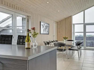 a kitchen with a table and chairs and a bottle of wine at Holiday Home Mavis - 800m from the sea by Interhome in Torsted