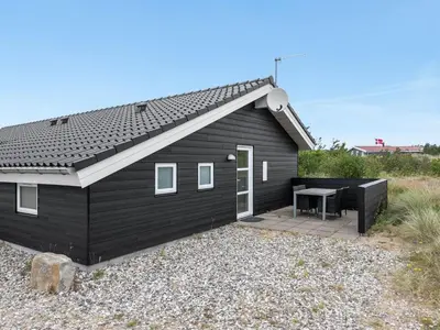 a black house with a patio and a table at Holiday Home Mavis - 800m from the sea by Interhome in Torsted