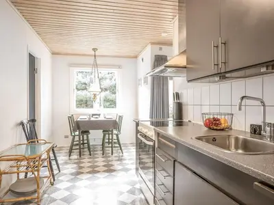 a kitchen with a sink and a table with chairs at Holiday Home Lökea - 800m from the sea by Interhome in Torsted