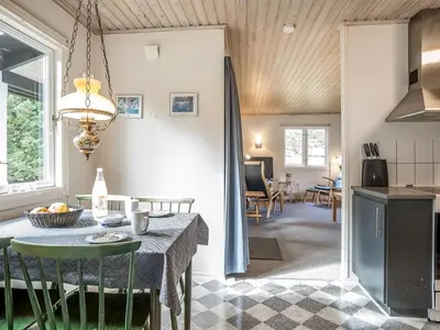 a kitchen and living room with a table and chairs at Holiday Home Lökea - 800m from the sea by Interhome in Torsted