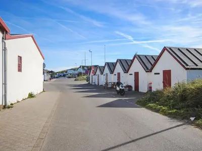 a row of white buildings with a motorcycle parked on a street at Holiday Home Lökea - 800m from the sea by Interhome in Torsted