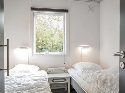 two beds in a bedroom with a window at Holiday Home Lökea - 800m from the sea by Interhome in Torsted