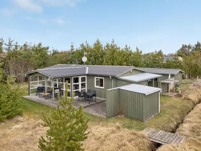 a green house with a porch and a deck at Holiday Home Asmir - 1-1km from the sea by Interhome in Torsted