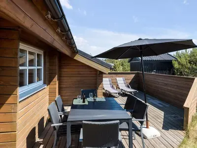 a wooden deck with a table and an umbrella at Holiday Home Eggerich - 900m from the sea by Interhome in Torsted