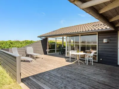 a wooden deck with a table and chairs on it at Holiday Home Rink - 150m from the sea by Interhome in Torsted