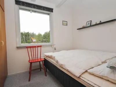 a bedroom with a bed and a chair and a window at Holiday Home Amber - 500m from the sea by Interhome in Torsted