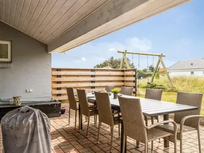 a patio with a table and chairs and a swing at Holiday Home Luzy - 600m from the sea by Interhome in Torsted