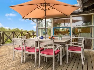 a table and chairs with an umbrella on a deck at Holiday Home Bodulf - 600m from the sea by Interhome in Torsted