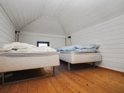 two beds in a room with white walls and wood floors at Holiday Home Duco - 300m from the sea by Interhome in Torsted