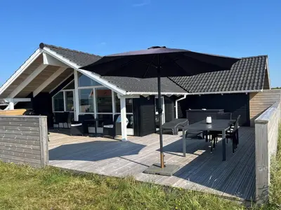 a wooden deck with a table and an umbrella at Holiday Home Thyrger - 550m from the sea by Interhome in Torsted