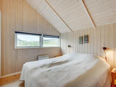 a bedroom with a large white bed and a window at Holiday Home Thyrger - 550m from the sea by Interhome in Torsted