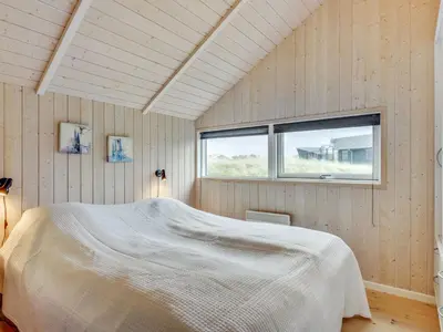 a bedroom with a white bed in a room with a window at Holiday Home Thyrger - 550m from the sea by Interhome in Torsted