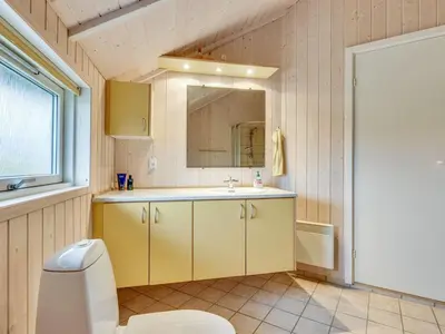 a bathroom with a sink and a toilet and a mirror at Holiday Home Thyrger - 550m from the sea by Interhome in Torsted