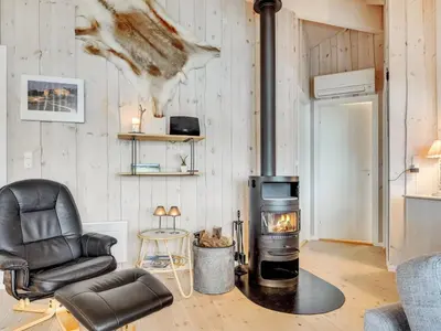 a living room with a wood stove and a chair at Holiday Home Thyrger - 550m from the sea by Interhome in Torsted