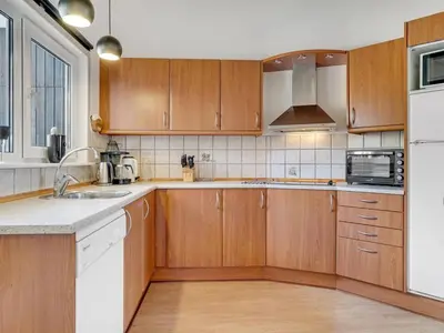 a kitchen with wooden cabinets and white appliances at Holiday Home Ivar - 900m from the sea by Interhome in Torsted