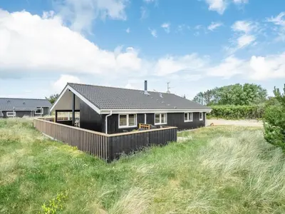 a black house on a grassy field at Holiday Home Ivar - 900m from the sea by Interhome in Torsted