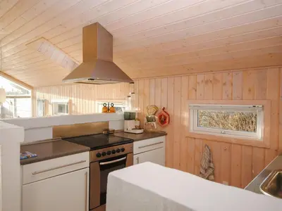 a kitchen with wooden walls and a stove top oven at Holiday Home Laurentia - 800m from the sea by Interhome in Torsted