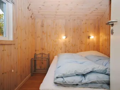 a bed in a room with a wooden wall at Holiday Home Laurentia - 800m from the sea by Interhome in Torsted