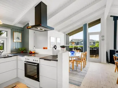 a kitchen with white cabinets and a dining room with a table at Holiday Home Laurentius - 300m from the sea by Interhome in Torsted