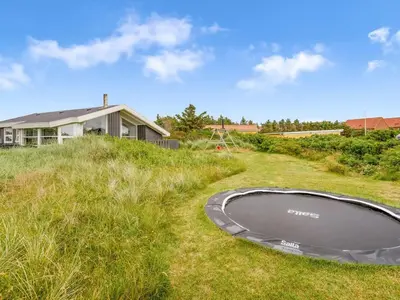a trampoline in the grass next to a house at Holiday Home Laurentius - 300m from the sea by Interhome in Torsted